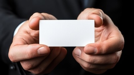 A man in a suit holding a white business card