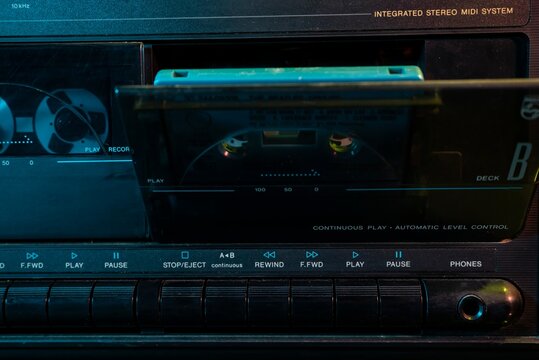Vintage stereo cassette deck playing a turquoise audio cassette in dark ambient light