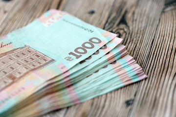 Big amount of ukrainian new one hundred hryvnia money bills with modern design on wooden background. Financial concept, business