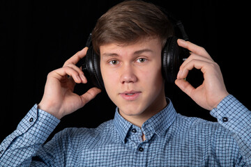 A teenager listens to music with headphones. The audio system.