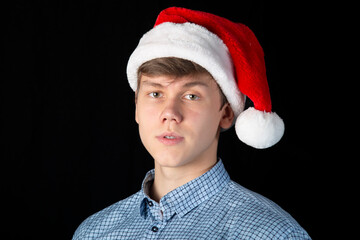 A young man in a red Christmas hat on a dark background