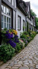 A peaceful cobblestone path in a German village lined with timber framed houses and vibrant spring flower boxes spilling over the windowsills 