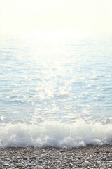 Fototapeta premium Serene coastal scene: sparkling ocean waves gently lapping on a pebble beach in Oregon.