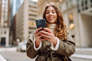 Portrait of happy woman with smartphone in the street city. Concept of vacation, blogging, technology, weekend.