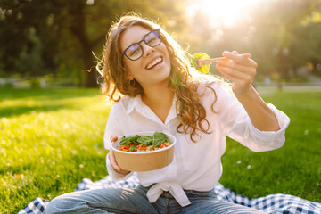 Young woman enjoying a healthy meal. Beautiful woman eating fresh vegetable salad outdoor....