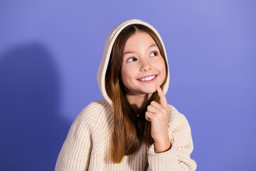 Smiling young girl in a cozy hoodie posing against a purple background, conveying happiness and...