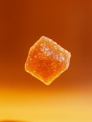 A single sugar cube floats against a gradient orange background, highlighting its texture and vibrant color.
