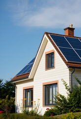 House with installed solar panels on roof. Alternative energy, magazine photoshoot, with white tones