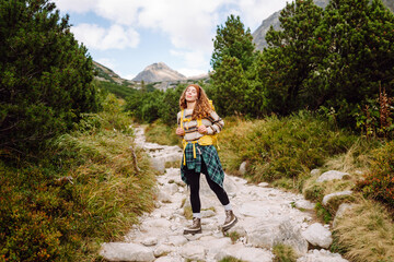 Naklejka premium Traveler woman is walking down a rocky path with a backpack. Travel, adventure. Concept of an active lifestyle.
