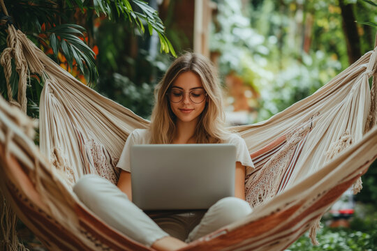 Young woman immersed in study while relaxing in a hammock surrounded by nature