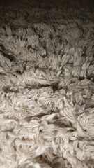 Close-up texture of a fluffy cream-colored fabric with intricate fiber patterns.