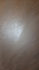 Fototapeta premium Close-up of a textured beige plaster wall with subtle sheen.