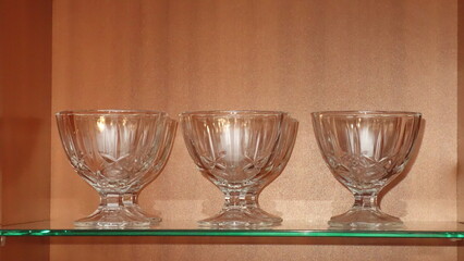 Elegant crystal glass bowls displayed on a shelf, shining under ambient light.