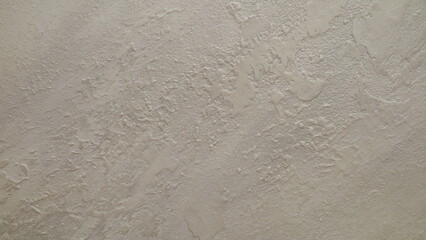 Textured beige wall surface with intricate patterns and subtle color variations.