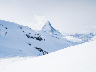 Fototapeta premium Matterhorn, Switzerland. Winter mountain landscape. A place for skiing. Zermatt ski resort. High rocks and snow. Mountain scene in Switzerland. Photo for postcards, backgrounds, wallpapers.