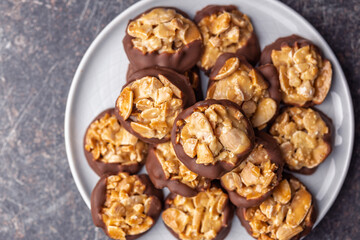Photography of chocolate Florentines cookies with almonds and chocolate on plate on black table. Top view.