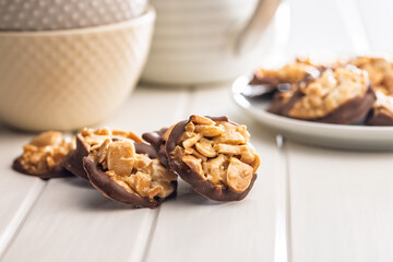 Photography of chocolate Florentines cookies with almonds and chocolate on white table.
