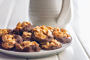 Photography of chocolate Florentines cookies with almonds and chocolate on plate on white table.