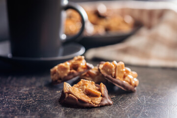 Photography of chocolate Florentines cookies with almonds and chocolate on black table.