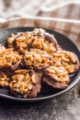 Photography of chocolate Florentines cookies with almonds and chocolate on plate on black table.