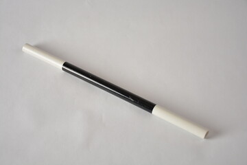 A sleek black and white magician's wand on a plain surface.