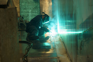 Fototapeta premium Welding sparks illuminate workshop as craftsman creates metal structure