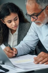 Fototapeta premium A couple sitting together at a table with laptops and paperwork, possibly collaborating or planning