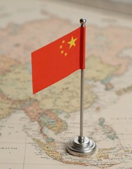 Chinese flag on miniature pole placed on a vintage map background. Concept of geography, travel, and international relations. Close-up composition for design and print.