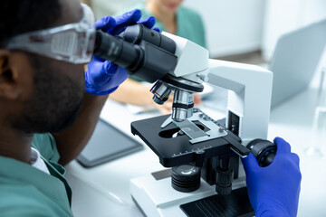 Man scientist using microscope for analysis testing and study vaccine results in lab or pharma
