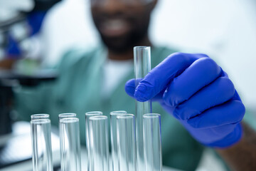 Male scientist in lab studying vaccine development and chemical reactions using test tubes