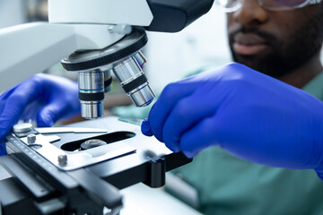 Man scientist using microscope for analysis testing and study vaccine results in lab or pharma