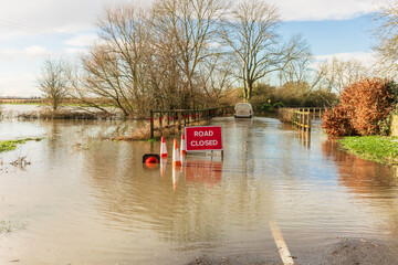 Severe flooding on the B1223 road between the villages of Ryther and Cawood in North Yorkshire with Road Closed sign and a vehicle ignoring the warning sign and driving through the water.  Copy space