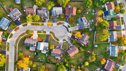 Aerial View of Suburban Cul-de-Sac Neighborhood. Top-down aerial shot of a suburban cul-de-sac surrounded by homes, driveways, and vibrant green yards in a peaceful neighborhood.