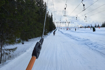 The view of riding a t-bar lift in going upwards a skiing slope in a winter landscape