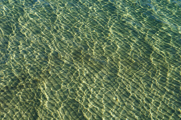 Transparent and crystal clear sea water with a sandy beach visible underneath