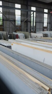 Colorful quartz and porcelain tile stone slab are standing in the factory warehouse. Kitchens and bathrooms countertop selection. Granite slabs are prepared for sale in store yard