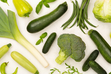 Different fresh green vegetables on concrete background, top view