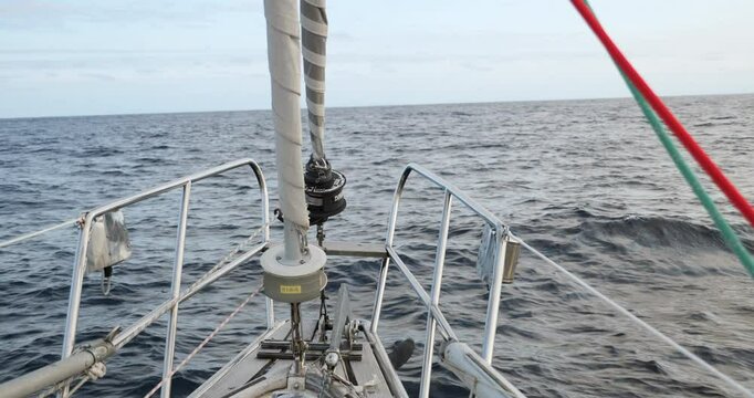 Bow of sailboat with two furling sails motoring across the Bay of Biscay