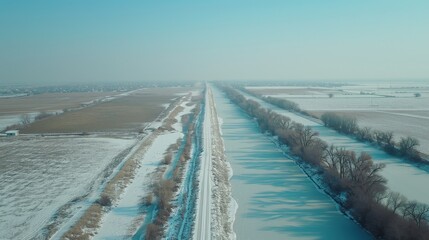 Tranquil winter scene featuring snowy trees and a frozen river beneath a clear blue sky