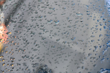 Raindrops delicately cling to a glass surface, creating a mesmerizing watery pattern