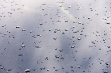 Raindrops dance on a reflective surface during a quiet afternoon in an urban setting