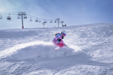 A vibrant and enthusiastic skier expertly carving through the soft, fresh powder snow, set against a stunning backdrop featuring mountain and ski lifts, Montgenevre ski village, Alps, France