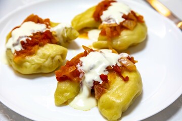 Classic Ukrainian food, perohê or veréneki stuffed with potatoes and cottage cheese and cooked, served with different types of sauce and salted and sour cream