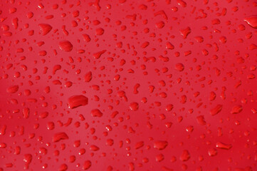Droplets dance on vibrant red surface after a refreshing rain shower