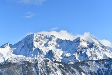 French alps on a sunny day under the clouds by winter covered with snow