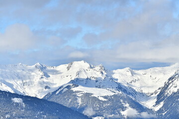 French alps on a sunny day under the clouds by winter covered with snow