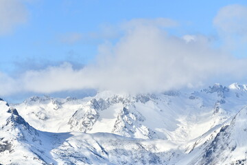 French alps on a sunny day under the clouds by winter covered with snow