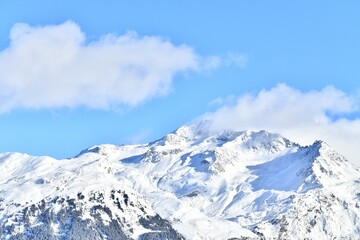 French alps on a sunny day under the clouds by winter covered with snow