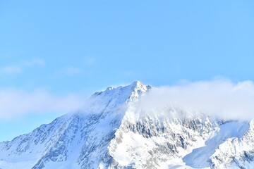French alps on a sunny day under the clouds by winter covered with snow