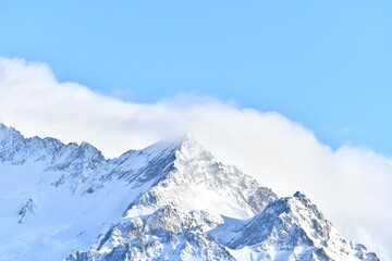 French alps on a sunny day under the clouds by winter covered with snow